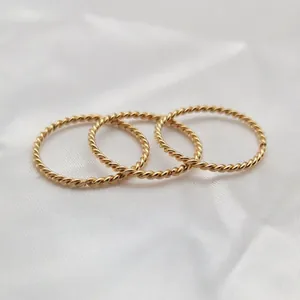 Close-up of minimalist gold twisted rope rings set in titanium steel