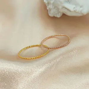 Detailed close-up of two interlocking twisted titanium steel rings in gold and rose gold.