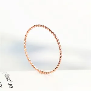 Close-up detail of a rose gold minimalist twisted rope ring made of titanium steel