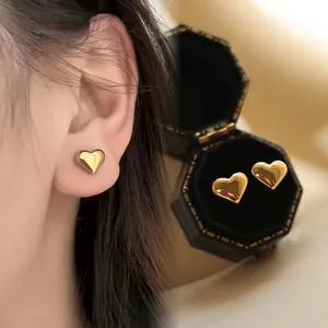 Vue détaillée de boucles d'oreilles cœur en or 18K sur l'oreille et en coffret.
