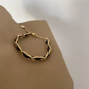 Close-up detail showing the gold chain and black leather interwoven bracelet design.
