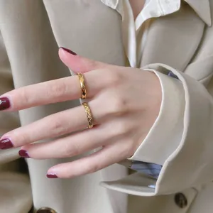 Primer plano de anillos dorados con patrón de rombos en una mano de estilo elegante