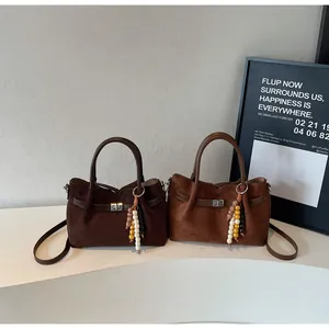 Vintage suede tote bag showing texture and beaded charm detail in two brown shades