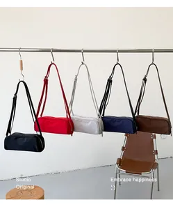 Variety of vintage nylon crossbody bags in multiple colors hanging on a studio rack