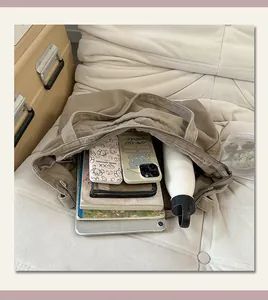 Dettaglio dell'ampio interno di una borsa tote in tela kaki con oggetti di uso quotidiano