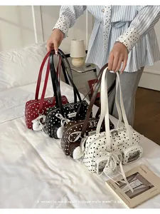 Four colors of vintage polka dot shoulder bags with pearl heart charms displayed on a bed.