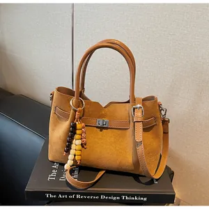 Close-up view of a vintage brown suede tote bag resting on a decorative design book.