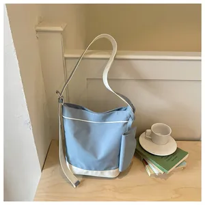 Large blue and white color-block canvas tote bag leaning against a white wooden railing