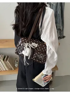 Detailed view of a brown polka-dot ita bag with heart charm and clear window pockets.