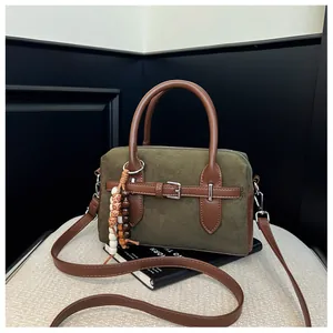 Detailed view of olive green suede Boston bag with brown leather handles and buckle.