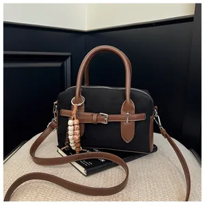 Retro suede pillow handbag with buckle detail and beaded charm in black and brown finish.