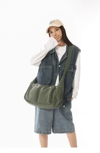Asiatisches Model mit einer großen grünen Segeltuchtasche für den täglichen Freizeitgebrauch