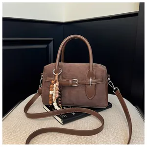 Vintage brown suede pillow bag with belt detail and wooden bead tassel accessory.