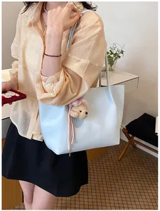 Detail view showing a light blue large capacity tote bag with a cute bear charm accessory