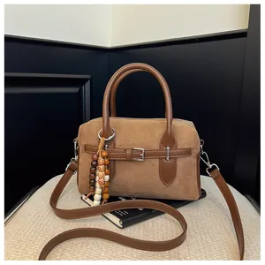 Detailed view of a retro brown suede pillow bag with a wooden bead charm on a book
