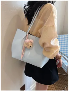 Detailed side view of a light blue commuter tote bag featuring a cute teddy bear charm
