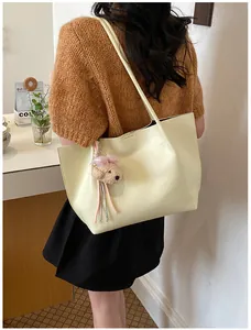Detailed view of an off-white large capacity tote bag with a cute bear charm accessory