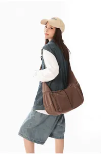 Große braune Canvas Umhängetasche, getragen von einem Model in lässiger Denim-Kleidung