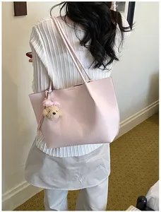 Detail view of elegant pink tote bag with a cute teddy bear charm, carried over shoulder
