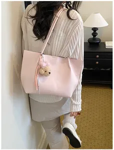 Detailed view of pink large capacity commute tote bag with a cute plush bear charm