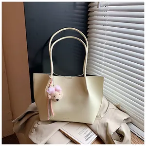 Elegant cream leather tote bag with a cute plush bear charm on a beige blazer backdrop