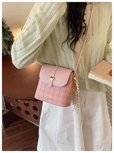 Elegant pink tweed bucket bag featuring a gold heart buckle and tennis racket charm