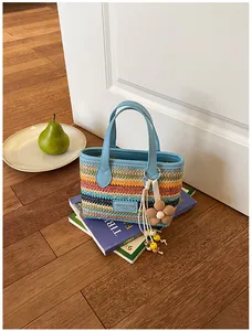 Nahaufnahme einer bunten handgewebten Strohtasche mit einem niedlichen Blumenanhänger.