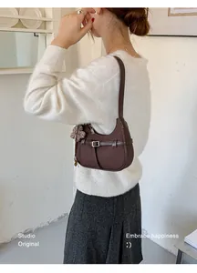 Bolso de hombro tejido marrón elegante llevado por una modelo en un entorno de estudio