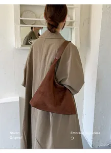 Modell trägt eine große braune Wildleder-Einkaufstasche im Retro-Maillard-Stil.
