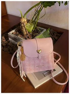 Chic pink plaid crossbody bag featuring a gold heart clasp and tennis racket charm