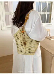 Detail of a hollow-out tote bag with wooden bead strap on model