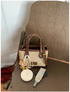 Handgefertigte gewebte Strohtasche mit Blumenanhänger und braunen Ledergriffen