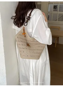 Detail view of a minimalist hollow-out beige tote bag with beaded strap on a model