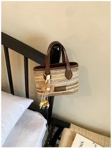 Detailansicht einer handgewebten Strohhandtasche mit Blumenanhänger für den Sommer