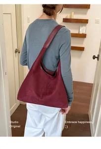 Elegante burgunderrote Schultertasche aus Wildleder am Modell für das herbstliche Styling