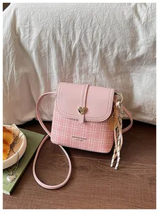 Detail view of pink tweed crossbody bag with heart buckle and tennis racket charm