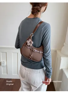 Detalle de bolso hobo marrón con dije de flor en el hombro de una modelo profesional.