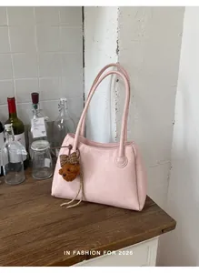 Detail of a minimalist pink tote bag with a cute bear charm in a lifestyle setting.