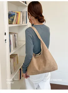 Nahaufnahme einer stylischen hobo-tasche aus kamel-wildleder an einer frau im haus