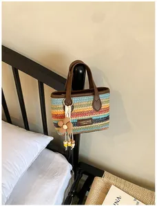 Handgefertigte farbenfroh gestreifte Strohtasche an einem schwarzen Holzbettrahmen