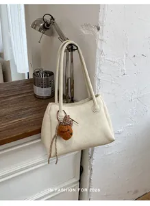 Detail view of a retro cream commuter tote bag with a teddy bear charm in a chic setting