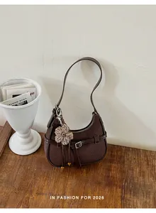 Vista detallada de un bolso de hombro tejido marrón vintage con colgante de flor