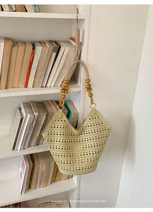 Close-up of a beige hollow-out tote bag with wooden bead handle accents on a white bookshelf