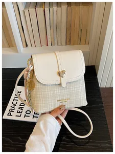 Close-up of a stylish women's crossbody bucket bag with heart clasp and checkered pattern.