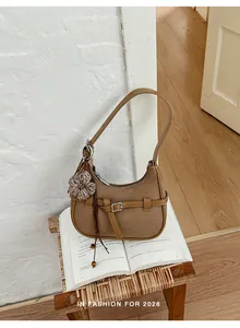 Bolso de hombro tejido marrón vintage con amuleto de flores sobre un libro abierto
