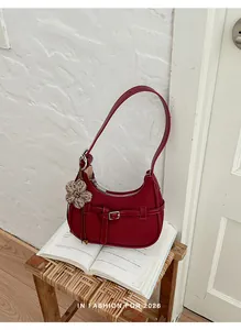 Vista detallada de bolso de hombro tejido rojo con hebilla en un taburete vintage