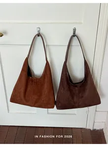Detaillierte Ansicht zweier Vintage-Wildleder-Hobotaschen in Braun und Hellbraun an einer Tür