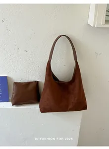 Detailaufnahme der braunen Wildleder-Hobo-Tasche mit passender Kosmetiktasche auf Weiß