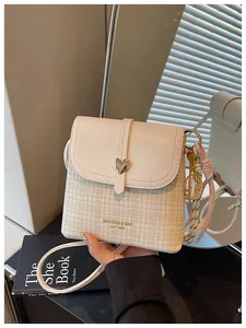 Close-up of a women's plaid crossbody bucket bag with heart buckle and tennis charm detail