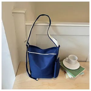 Korean style navy blue canvas tote bag with white contrast trim on a wooden desk